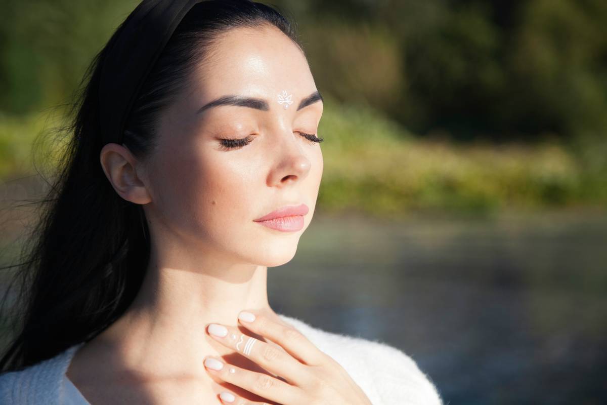 Person sitting comfortably with eyes closed, gently resting one hand on chest and one on abdomen, soft natural light — anxiety meditations on the anxious mind
