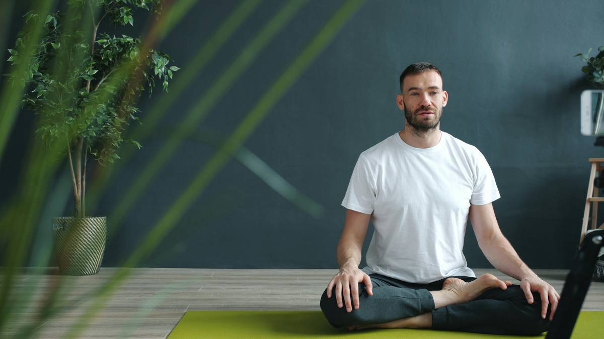 Woman listening to play meditations for anxiety on headphones while sitting peacefully by a window